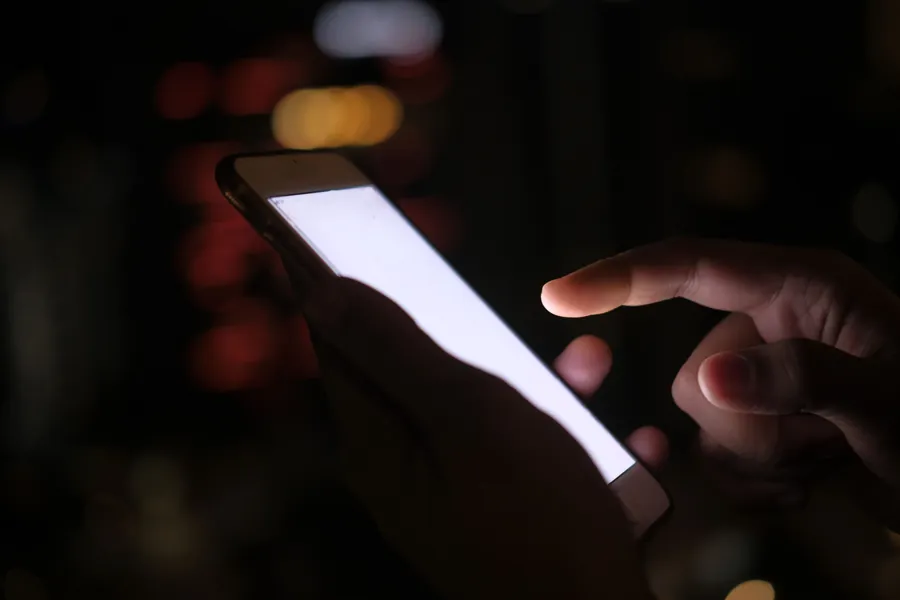 Personne consultant son smartphone dans la pénombre