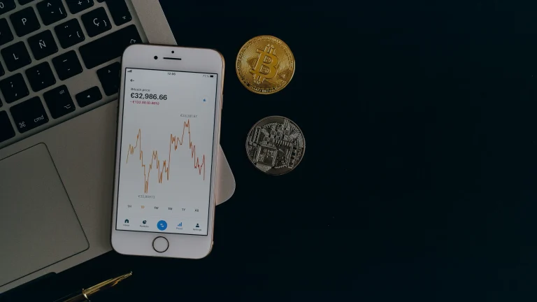 Un smartphone affichant un cours de cryptomonnaie posé sur un ordinateur portable