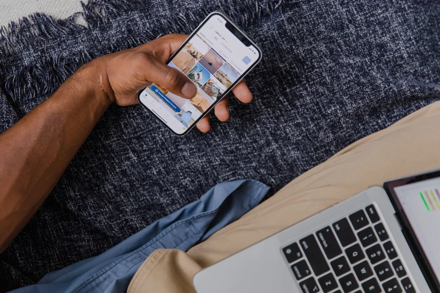 Personne qui consulte une application bancaire sur son smartphone devant un ordinateur portable