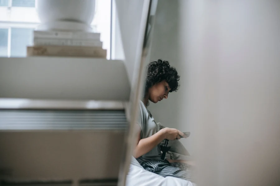 Femme assise chez elle qui lit un message sur son téléphone portable